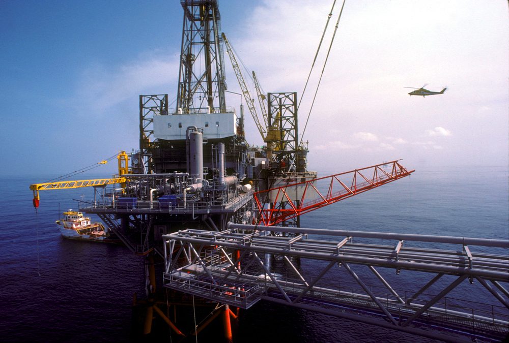 Helicopter approaching an offshore platform with crane
