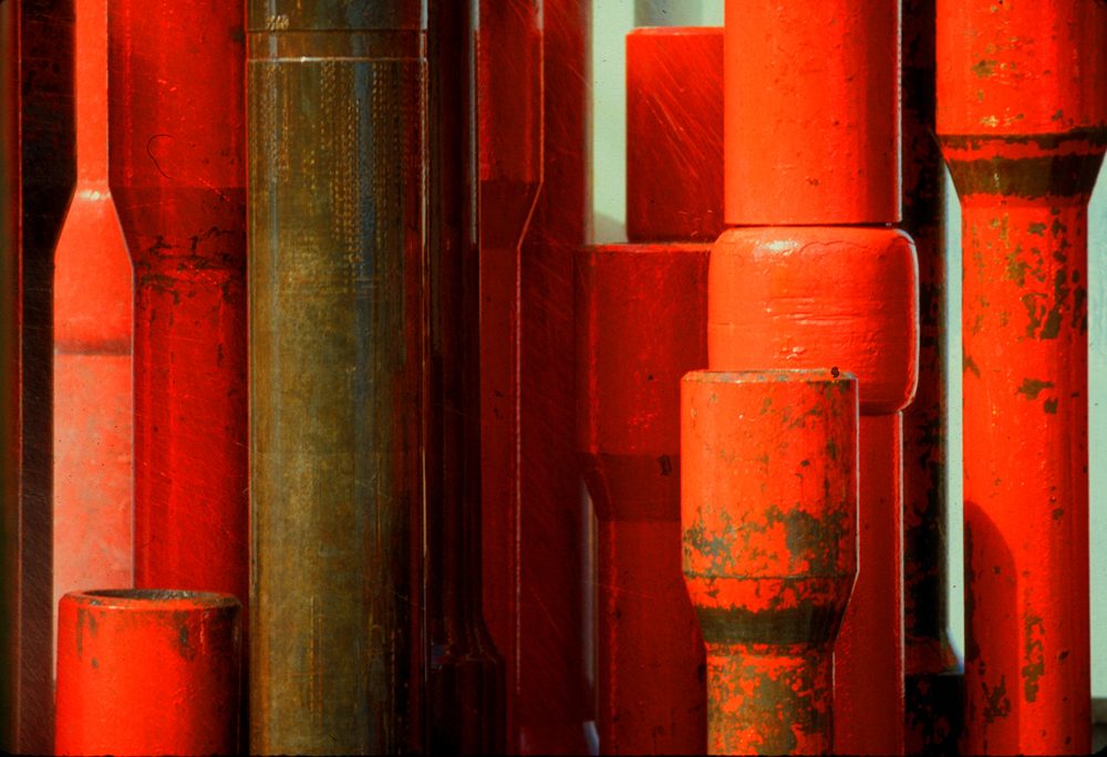 Red and orange painted pipe stacked in a yard