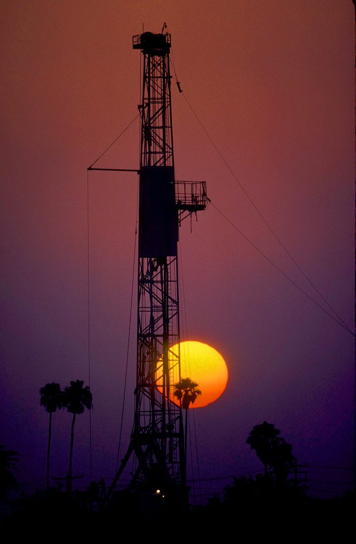 Drilling rig framed against a setting sun