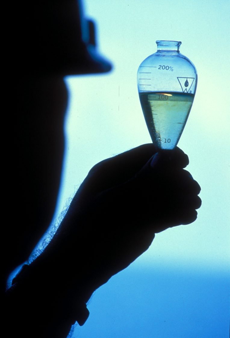 Hand holding a glass sample flask against light